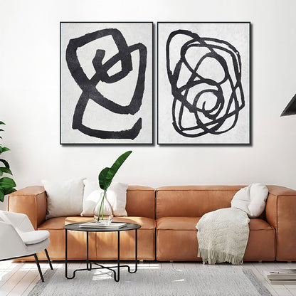 Modern living room with abstract black artwork on a white wall above a brown sofa.