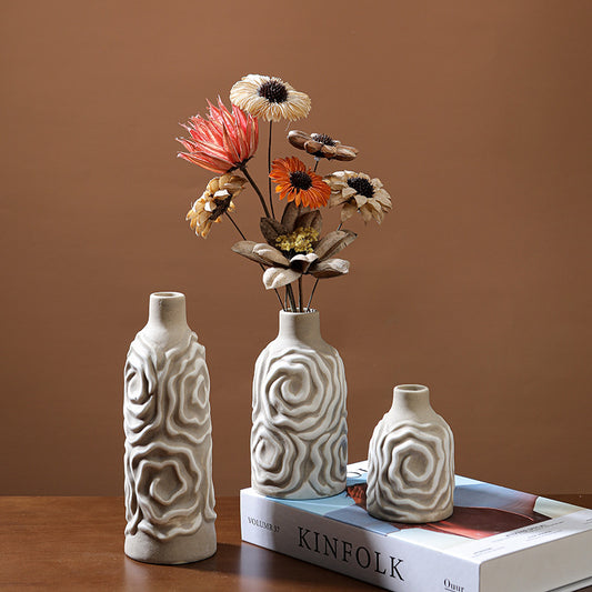 Three ceramic vases with textured designs on a book against a brown background