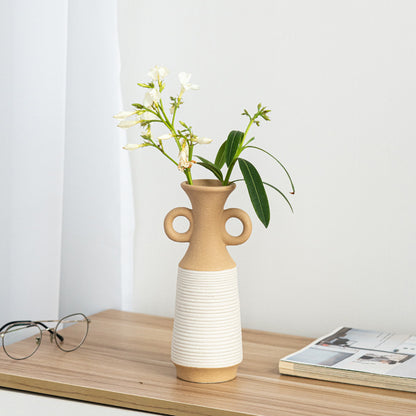 Beige and white vase with flowers on a wooden surface