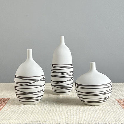 Three white vases with black wavy patterns on a gray background