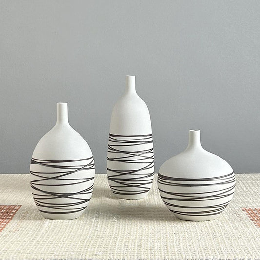 Three white vases with black wavy patterns on a gray background