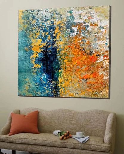 Abstract painting with blue, orange, and yellow colors on a wall above a beige sofa.