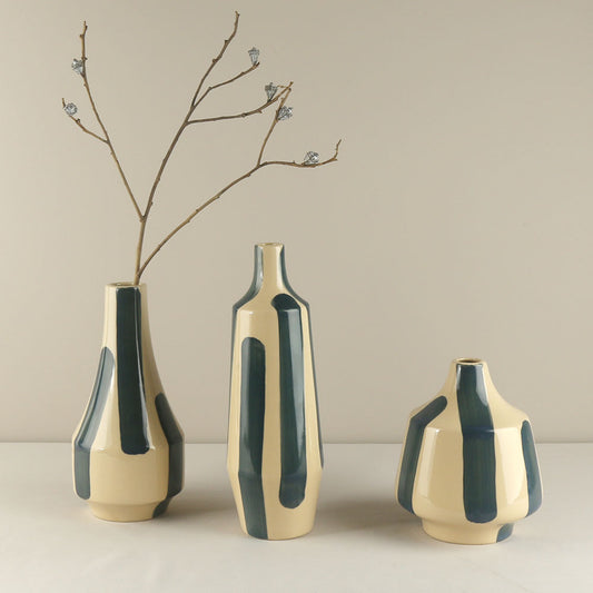 Three ceramic vases with green and beige design on a neutral background
