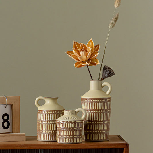 Three ceramic vases with decorative patterns on a wooden surface against a plain background