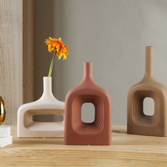 Three ceramic vases with unique designs on a wooden surface.