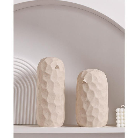 Two beige ceramic vases on a white shelf with a neutral wall background