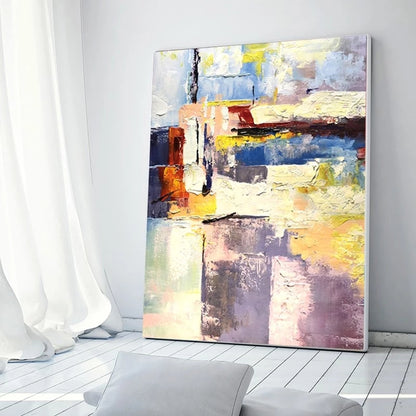 Abstract painting on a wall in a room with white curtains and a gray chair.