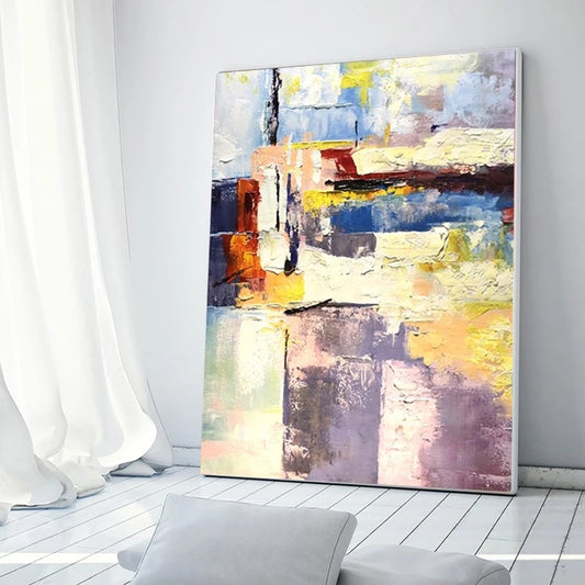 Abstract painting on a wall in a room with white curtains and a gray chair.