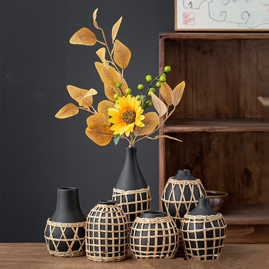 Decorative vases with a sunflower arrangement on a wooden surface against a dark wall.
