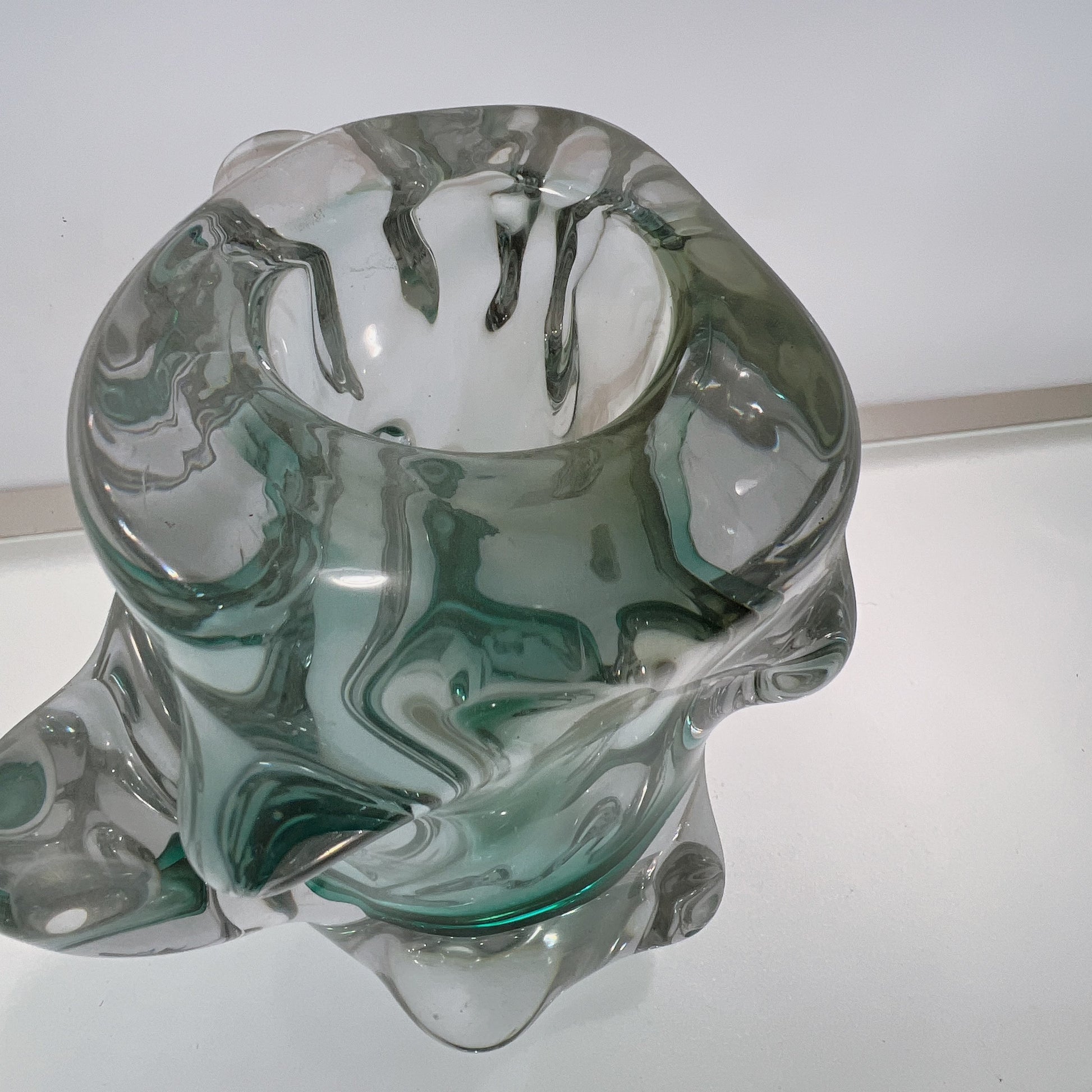 Glass sculpture with green and clear patterns on a white background