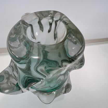 Glass sculpture with green and clear patterns on a white background