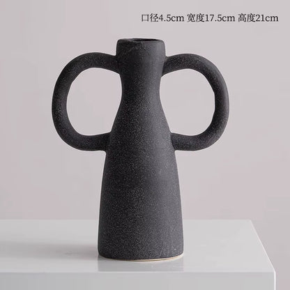 Black ceramic vase with handles on a light gray background