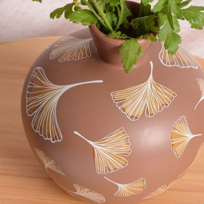 Ceramic vase with leaf pattern on a wooden surface