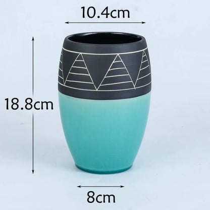 Teal and black ceramic cup with geometric design, shown with measurements on a white background.