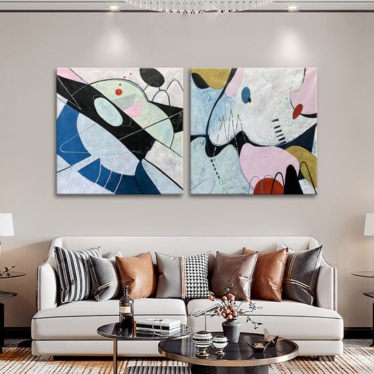 Two abstract art pieces on a wall above a sofa in a living room.