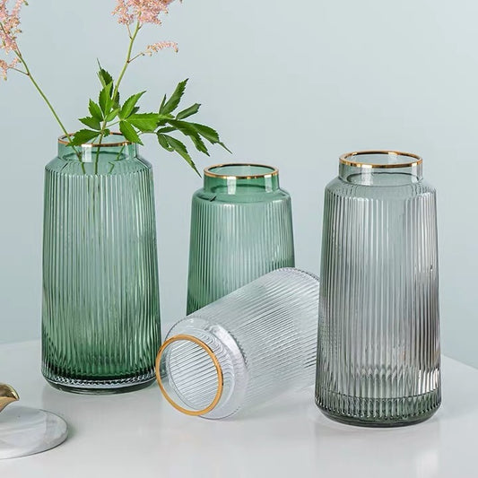 Set of glass vases with ribbed design and gold rims on a light blue background