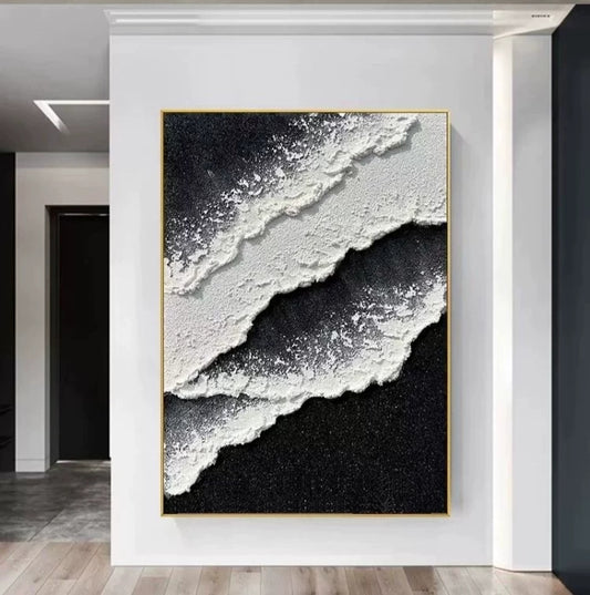 Abstract art piece with black, white, and gray textures in a gold frame on a wall.