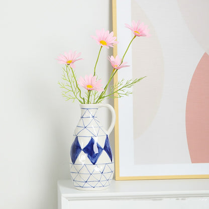 Decorative vase with pink flowers on a shelf next to a framed picture