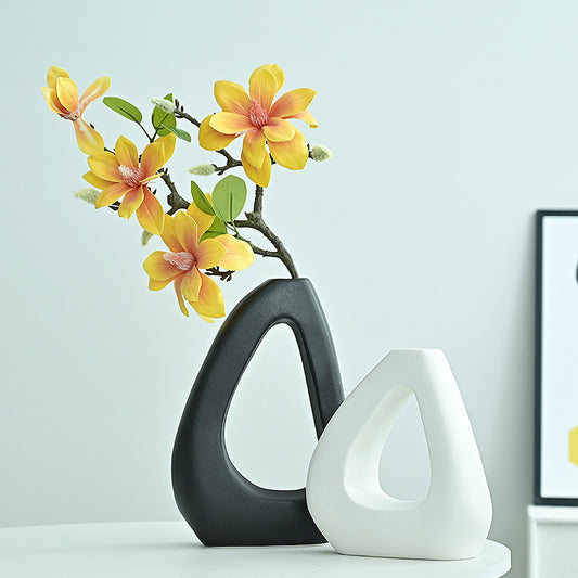 Two ceramic vases, one black and one white, with yellow flowers on a light blue background.