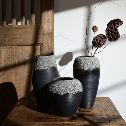 Two black textured vases with white accents on a wooden surface.