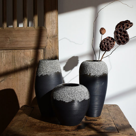 Two black textured vases with white accents on a wooden surface.