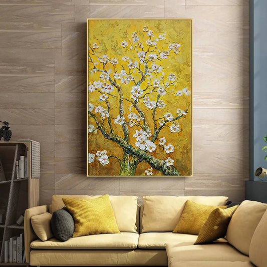 Framed artwork of a floral branch on a wall above a beige sofa with yellow cushions.