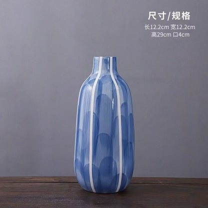 Blue and white striped vase on a wooden surface with a gray background