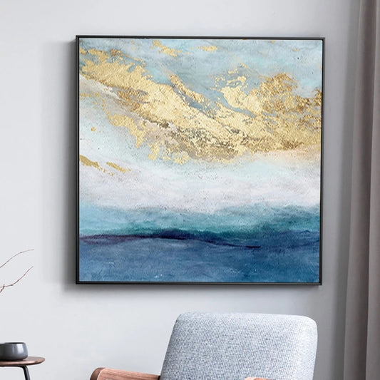 Abstract painting with gold and blue tones on a wall above a chair.