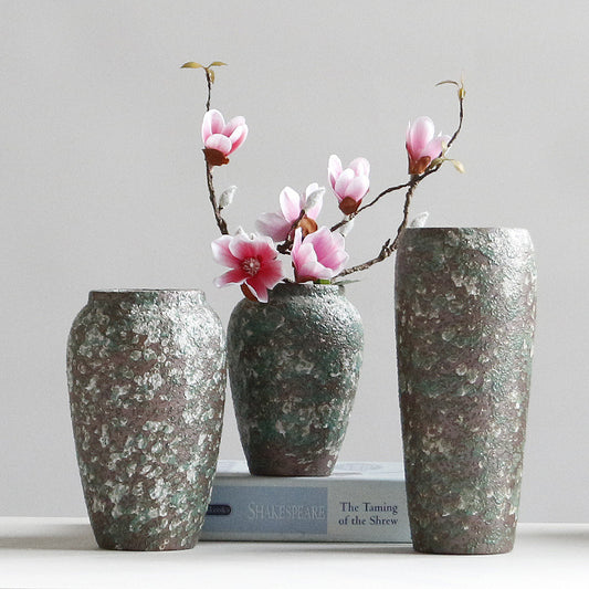 Three textured vases with pink flowers on a gray background