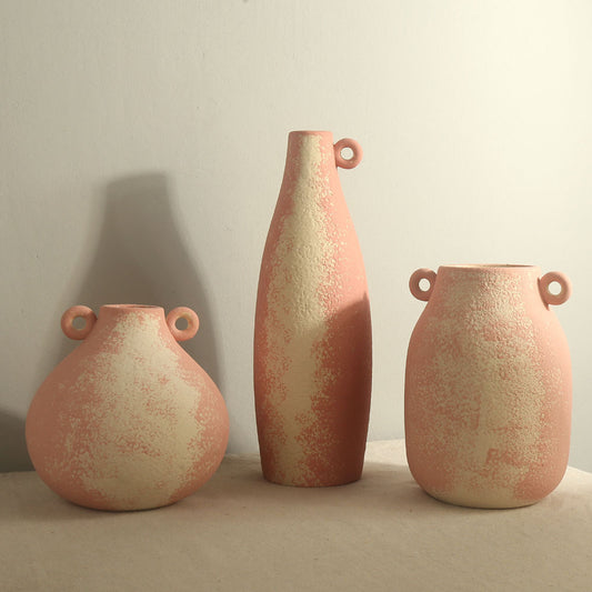 Three ceramic vases with textured surface and handles on a neutral background