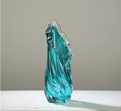 Turquoise glass sculpture on a white surface with a gray background