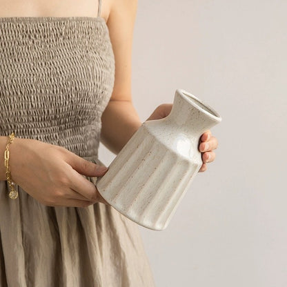 Person holding a ceramic vase against a plain background