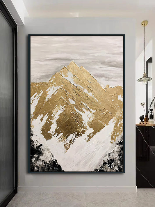 Abstract art of a mountain in gold and white on a gray wall.