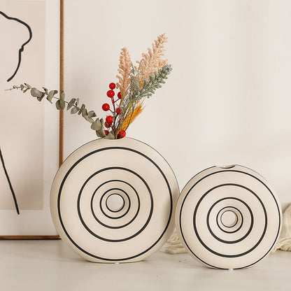 Two decorative vases with circular patterns on a light surface.
