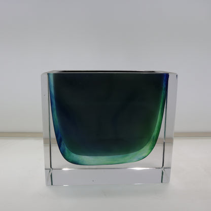 Clear glass vase with a greenish-blue gradient on a white background