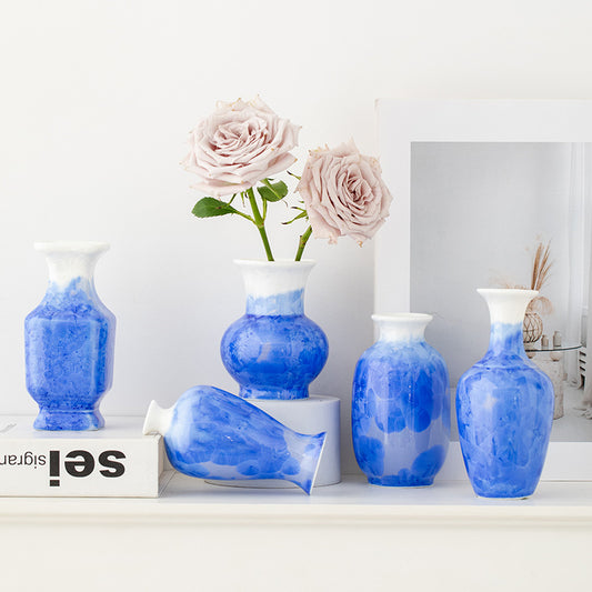 Set of blue and white vases with pink roses on a white surface