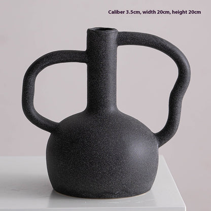 Black ceramic vase with handles on a light gray background