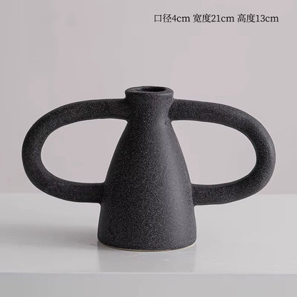 Black ceramic vase with dual handles on a light gray background