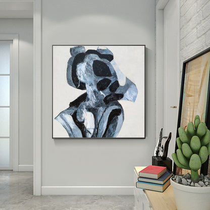 Abstract art piece on a wall in a modern interior setting with books and a plant.