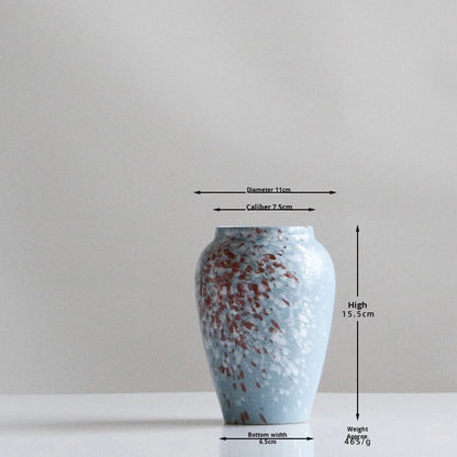 Blue ceramic vase with measurement markings on a gray background
