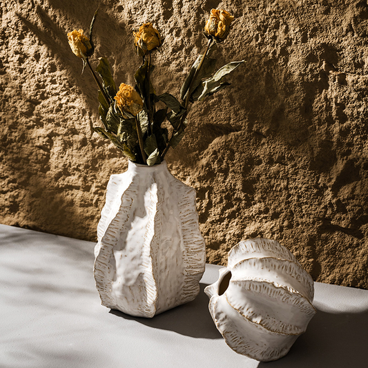 White textured vase with dried flowers against a stone wall