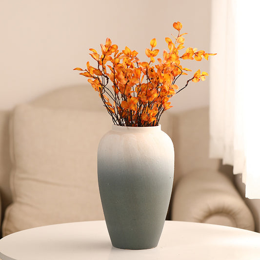 Gray vase with orange flowers on a table against a neutral background