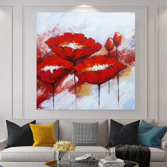 Abstract painting of red flowers on a wall above a sofa with colorful cushions.