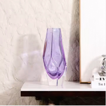 Purple glass vase on a white surface with a neutral background