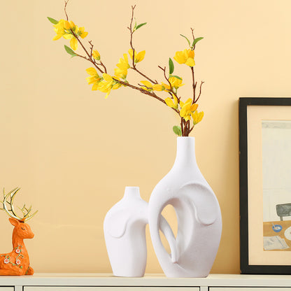 Decorative scene with white vases, a yellow flower arrangement, and a deer figurine on a beige wall background.