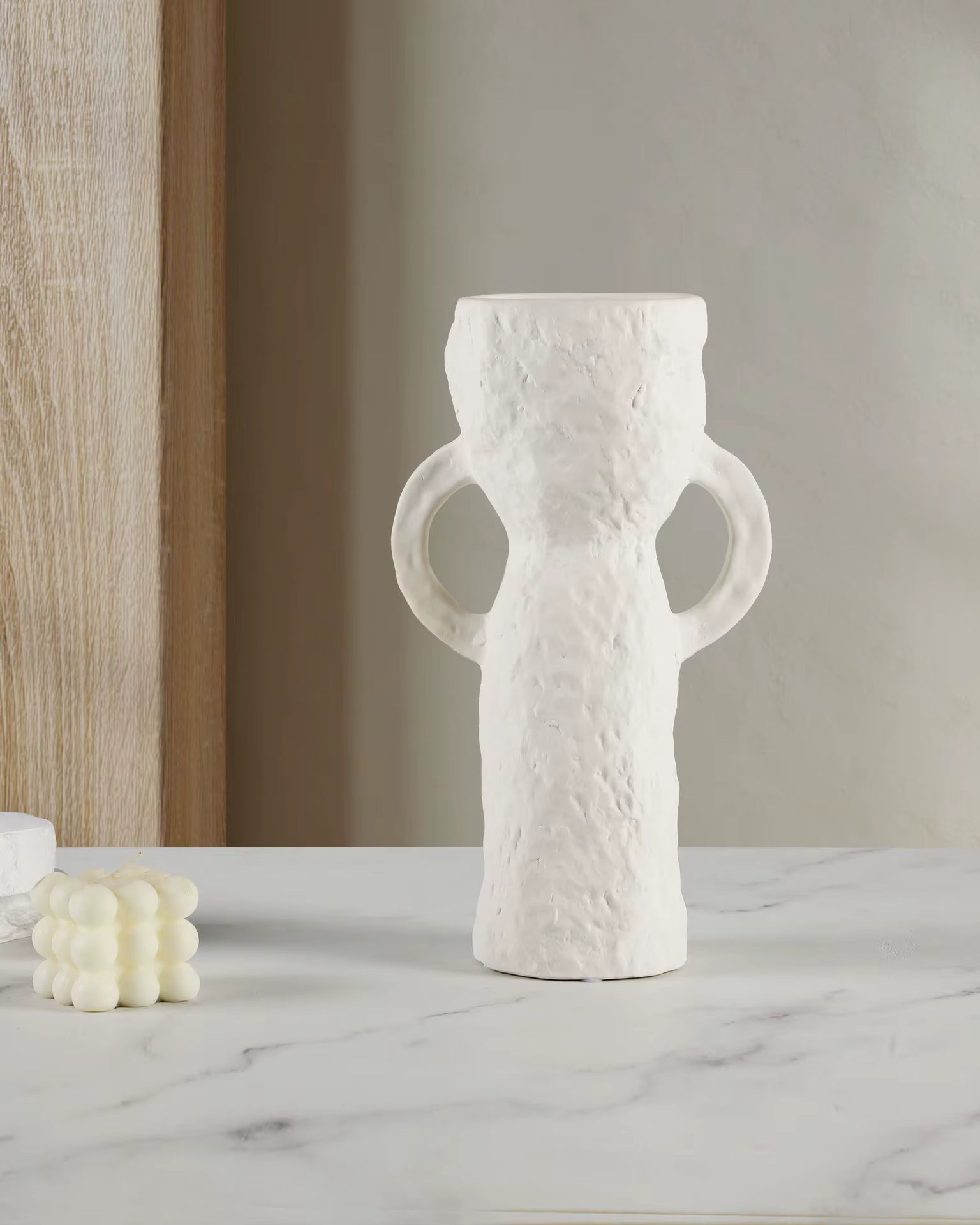 White textured vase with handles on a marble surface