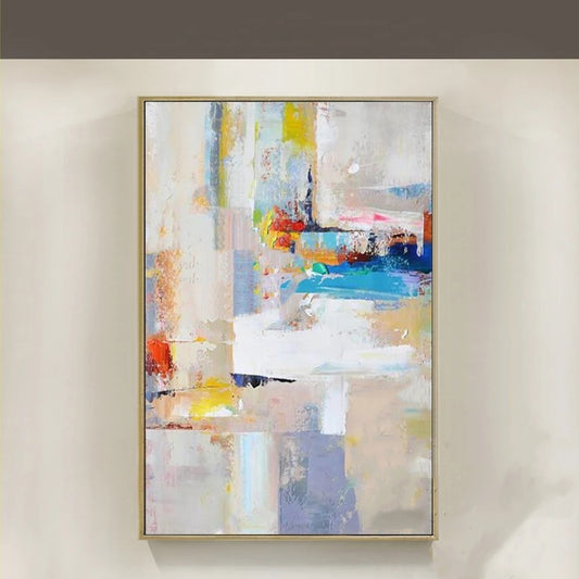 Abstract painting with colorful brush strokes in a gold frame on a beige wall.