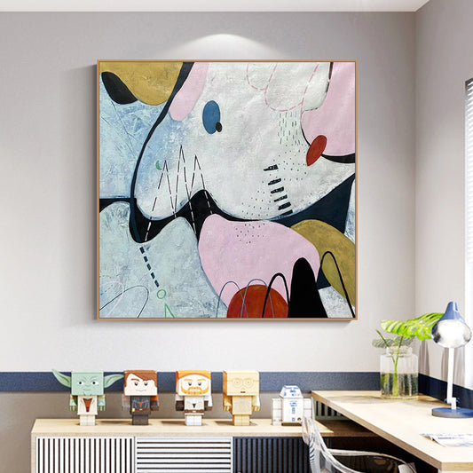 Abstract artwork on a wall above a desk with decorative items.