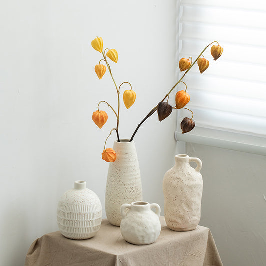 Set of four ceramic vases with textured surfaces on a table against a white wall.