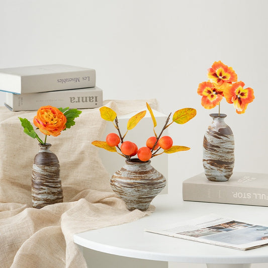 Three decorative vases with flowers on a table against a white background